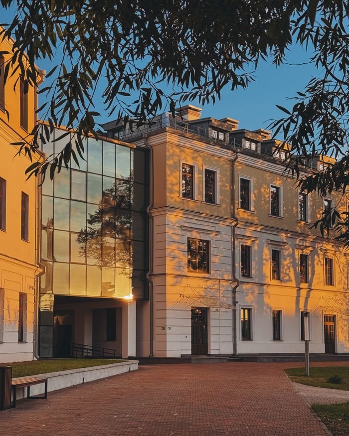 A modern architectural building bathed in sunset light, featuring reflective glass and classic design.