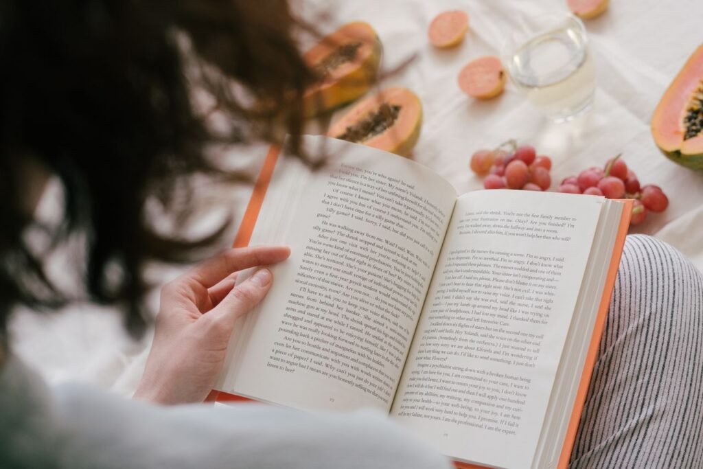 Mastering the First Impression: Your intriguing post title goes here A person enjoys reading a book surrounded by fresh papaya, grapes, and a drink, creating a cozy indoor scene.